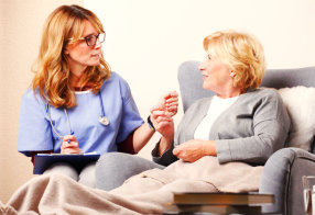 caregiver with stethoscope checking on senior woman