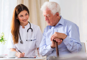 nurse with stethoscope checking on senior man